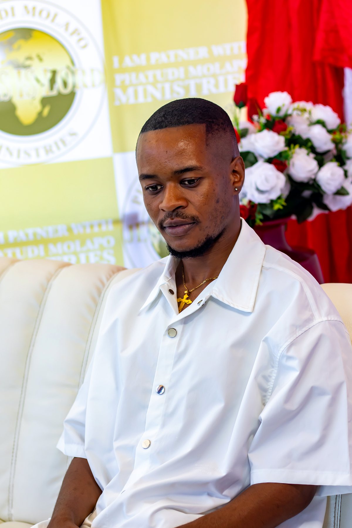 Young man seated at the ministry photo backdrop